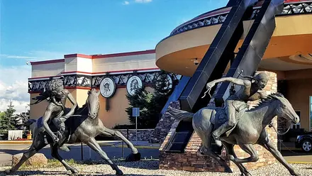 Bronze riders on horseback in front of the curved entrance of Painted Hand Casino in Yorkton